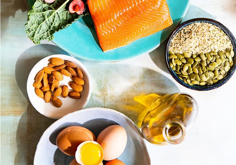 Cibo in tavola con tutti macronutrienti. Nella foto si vedono: salmone, uova, mandorle, semi, olio e foglia di cavolo.