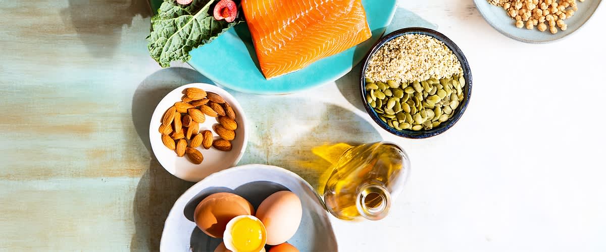 Cibo in tavola con tutti macronutrienti. Nella foto si vedono: salmone, uova, mandorle, semi, olio e foglia di cavolo.