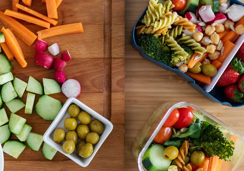 Verdure fresche e contenitori con insalate su un tavolo di legno