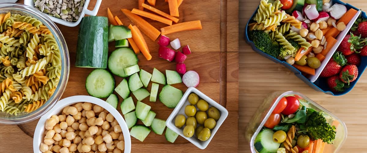 Verdure fresche e contenitori con insalate su un tavolo di legno