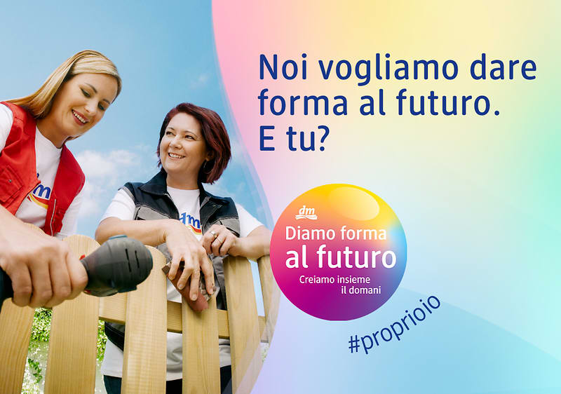 Due persone parlano vicino a una staccionata. Testo: "Noi vogliamo dare forma al futuro. E tu?" e "Diamo forma al futuro".