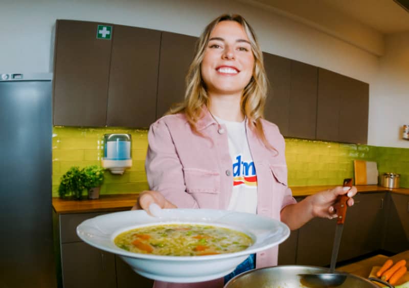 Una persona in cucina tiene un piatto di zuppa di verdure.