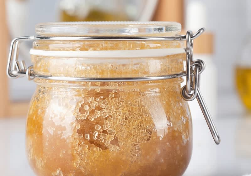 Barattolo di peeling fai da te con miele e zucchero su tavolo