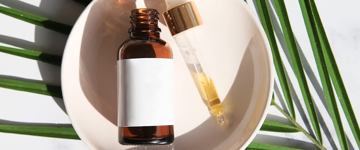 Boccetta di olio di ricino e contagocce su piatto con foglia verde