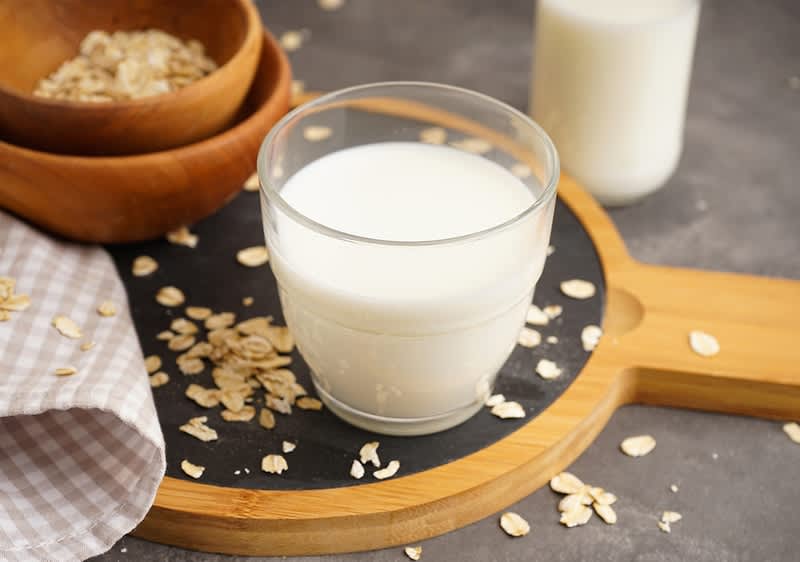 Bicchiere di latte d'avena su tagliere con fiocchi d'avena