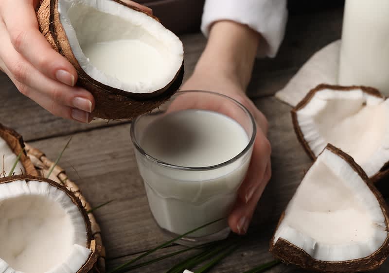 Latte di cocco versato in un bicchiere con noci di cocco