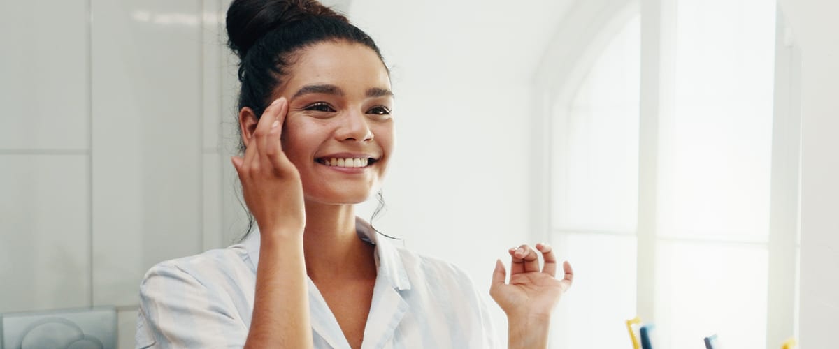 Una ragazza in pigiama si guarda allo specchio sorridendo.