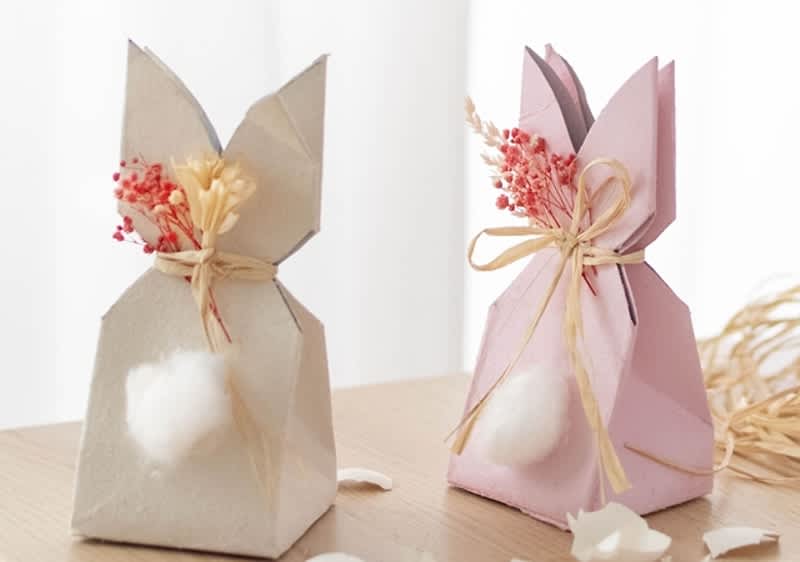 Cestini di Pasqua a forma di coniglietti con fiori e fiocchi su tavolo