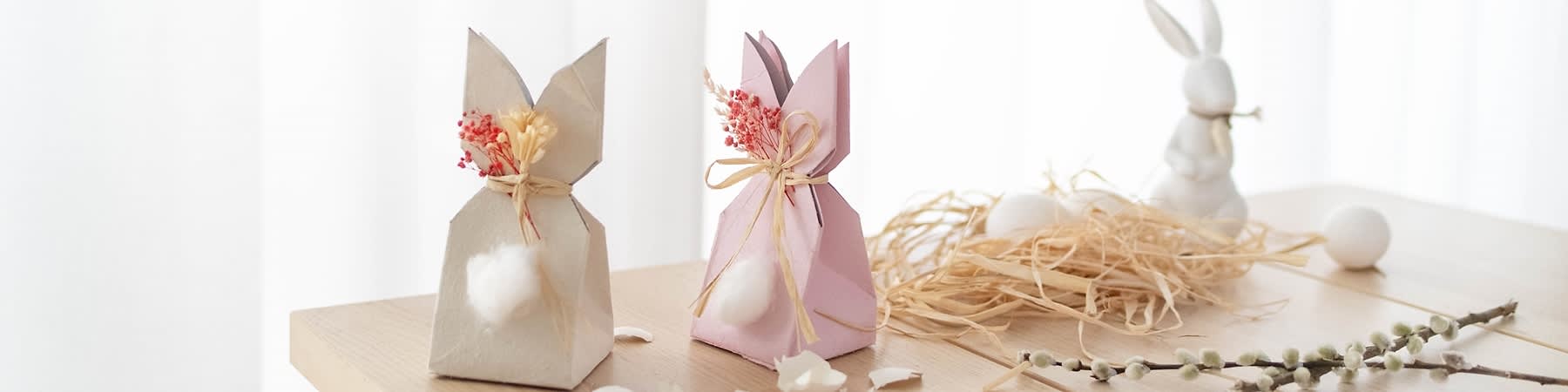 Cestini di Pasqua a forma di coniglietti con fiori e fiocchi su tavolo