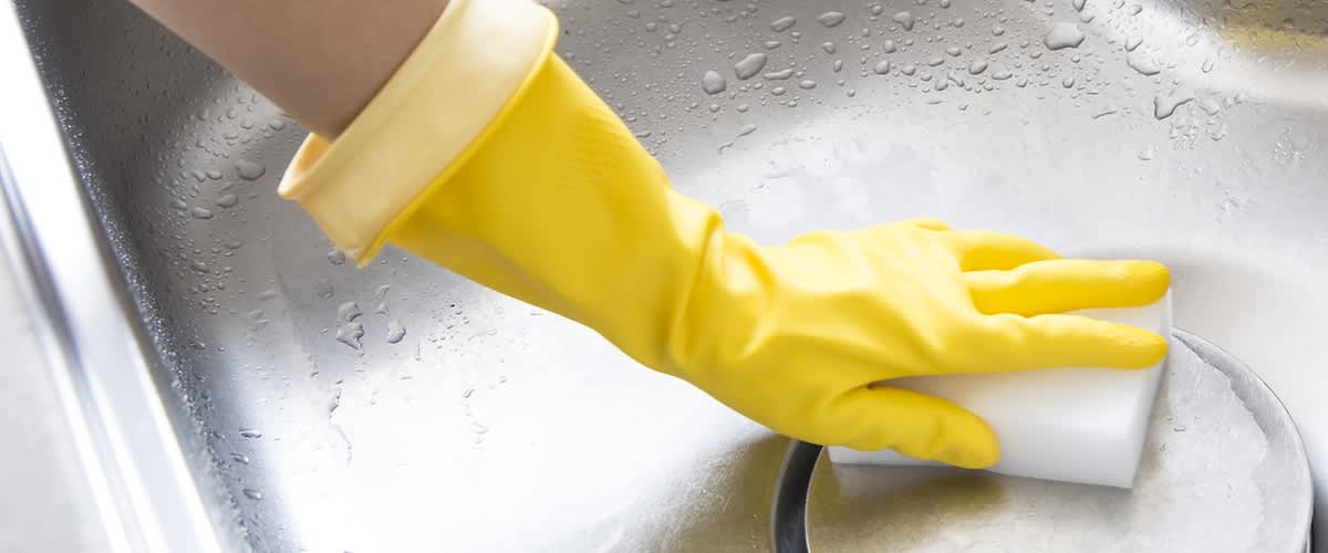 Guanto giallo pulisce lavandino con spugna