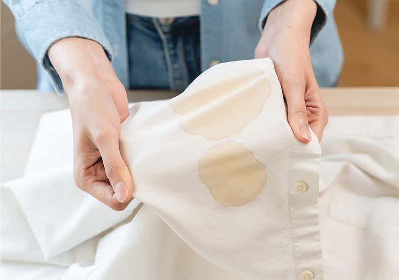 Persona con in mano una camicia bianca sporca di macchie di caffè