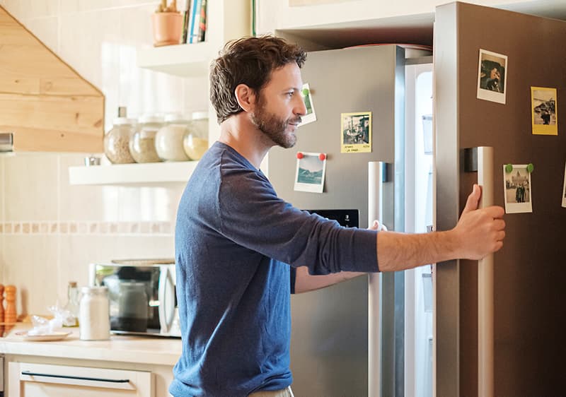 Un uomo apre il frigo.