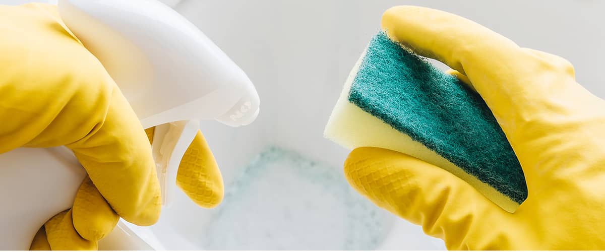 Pulizia del water con guanti gialli, spray detergente e spugna