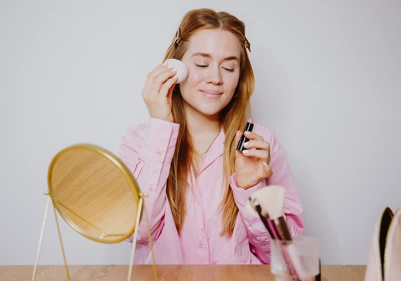 Una ragazza si applica il rossetto come blush.