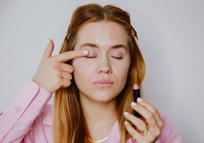 Una ragazza si applica il rossetto come ombretto.