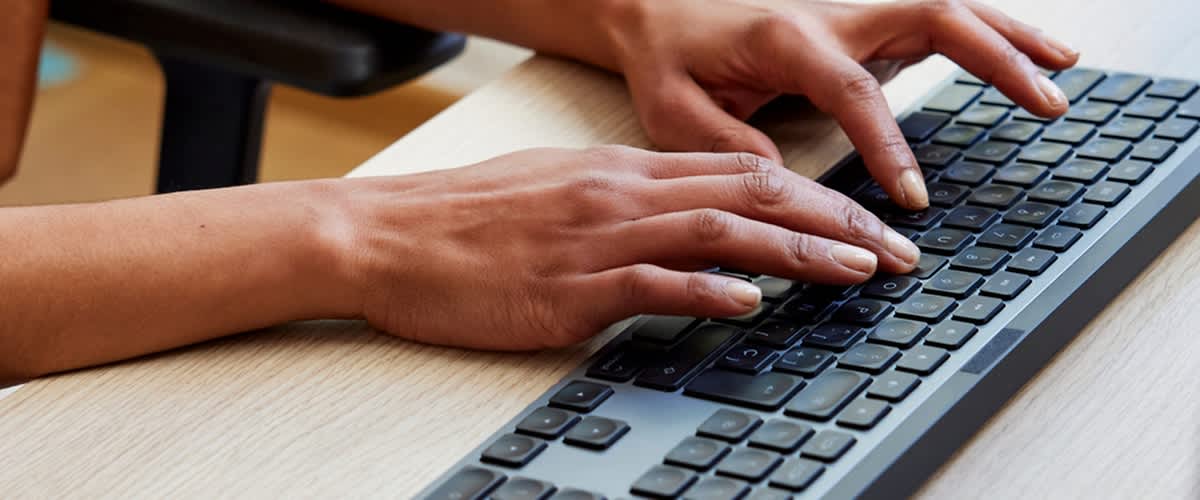 Mani che digitano su una tastiera computer sulla scrivania