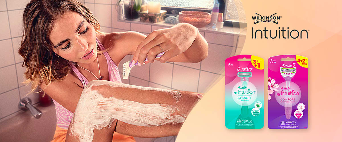 Rasoio Intuition Wilkinson donna che si rade la gamba con confezioni del prodotto sullo sfondo