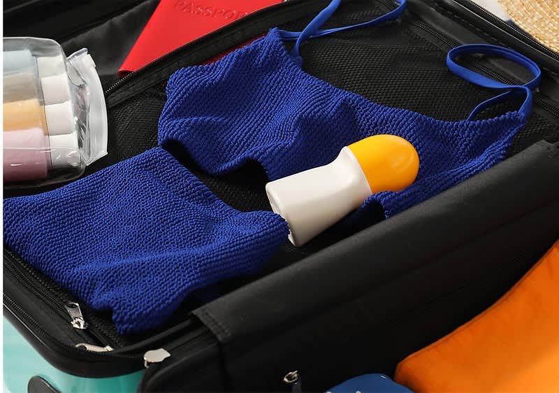 Costume e deodorante dentro ad una valigia aperta