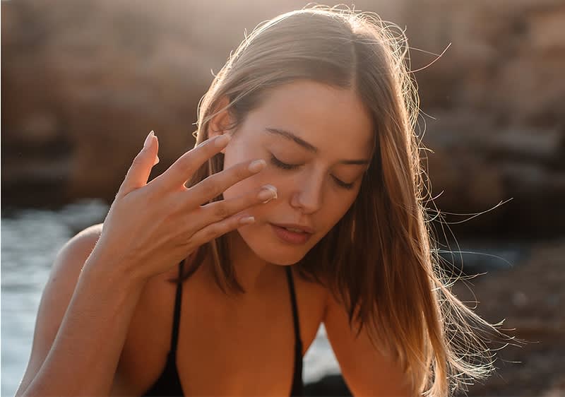 Ragazza sulla spiaggia che si mette la crema solare