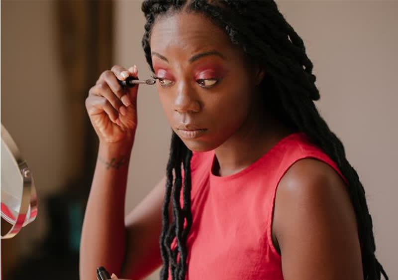 Donna con maglia rossa si mette il mascara.