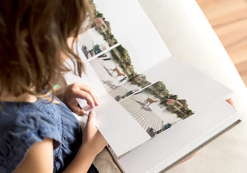 Bambina che sfoglia un libro fotografico con pagine di foto all'aperto