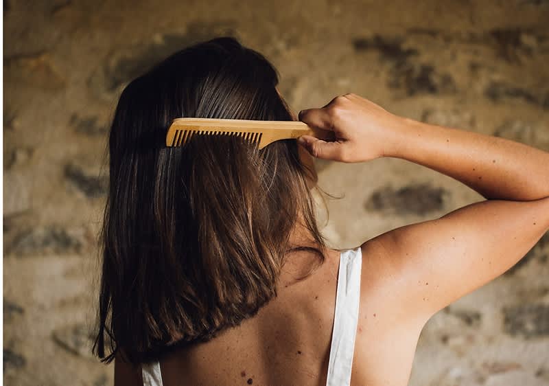 Donna di spalle che pettina i capelli con un pettine