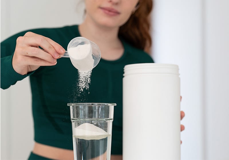 Donna versa aroma in polvere in un bicchiere d'acqua