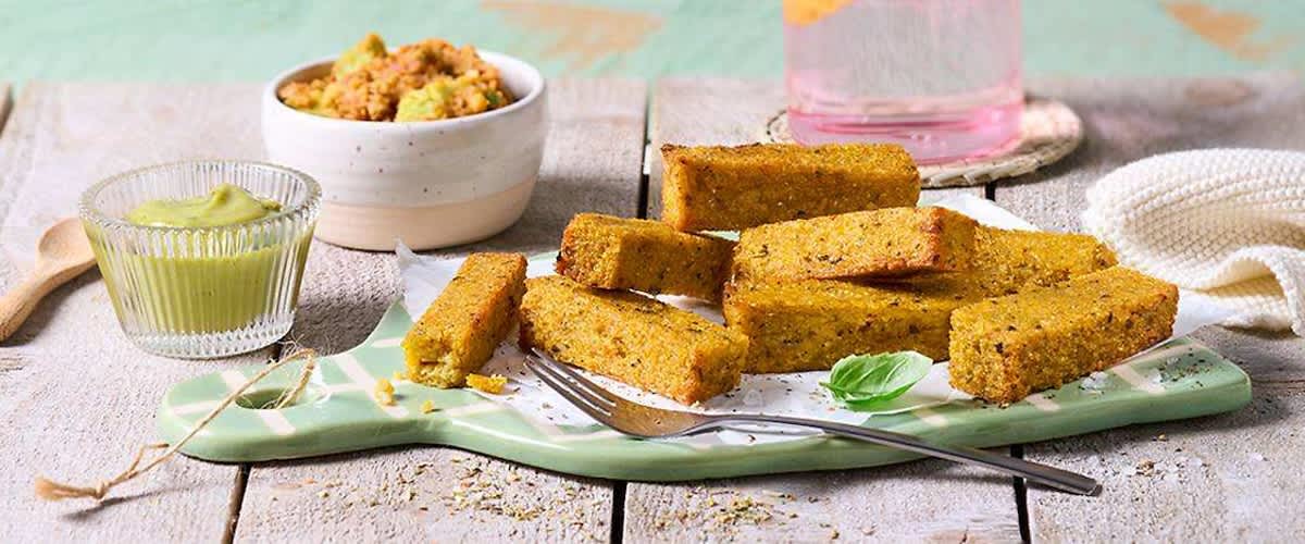Bastoncini di polenta croccante serviti su piatto con forchetta e basilico.