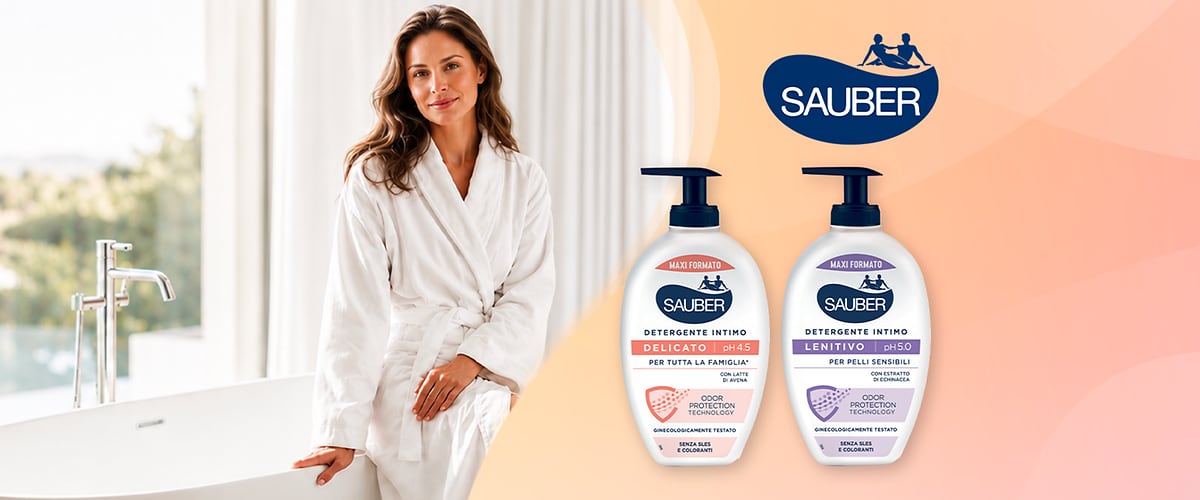 Donna sorridente in accappatoio bianco, a destra due flaconi di detergente intimo Sauber: delicato e lenitivo.