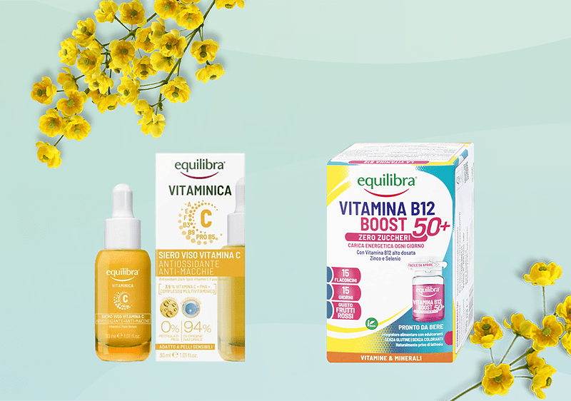 Due confezioni di prodotti Equilibra su sfondo verde chiaro con fiori gialli ai lati: a sinistra confezione e flacone con contagocce di siero viso alla vitamina C con etichetta arancione; a destra scatola di integratore Vitamina B12 Boost 50+ con colori bianco, blu e rosa, indicazione zero zuccheri e pronto da bere