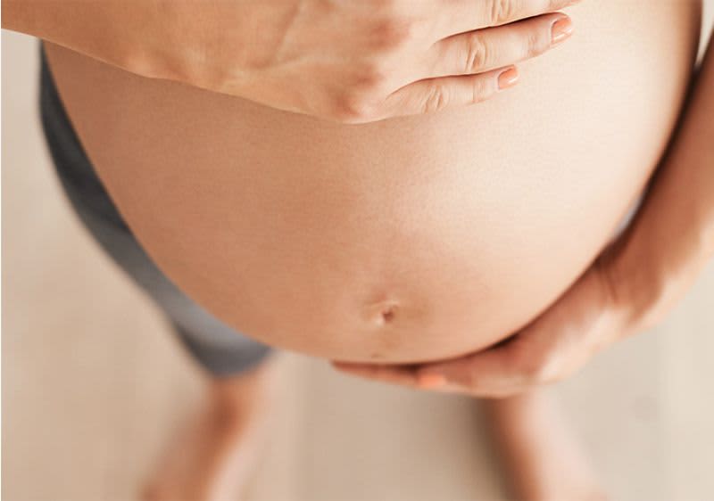 Kobieta obejmuje swój ciążowy brzuch