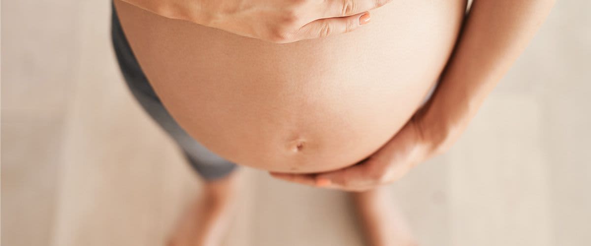 Kobieta obejmuje swój ciążowy brzuch