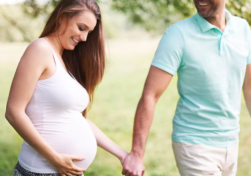 Kobieta w ciąży oraz mężczyzna trzymający się za ręce
