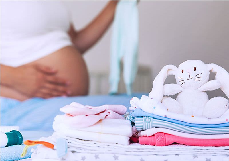 Kobieta w ciąży składa ubranka dla dziecka
