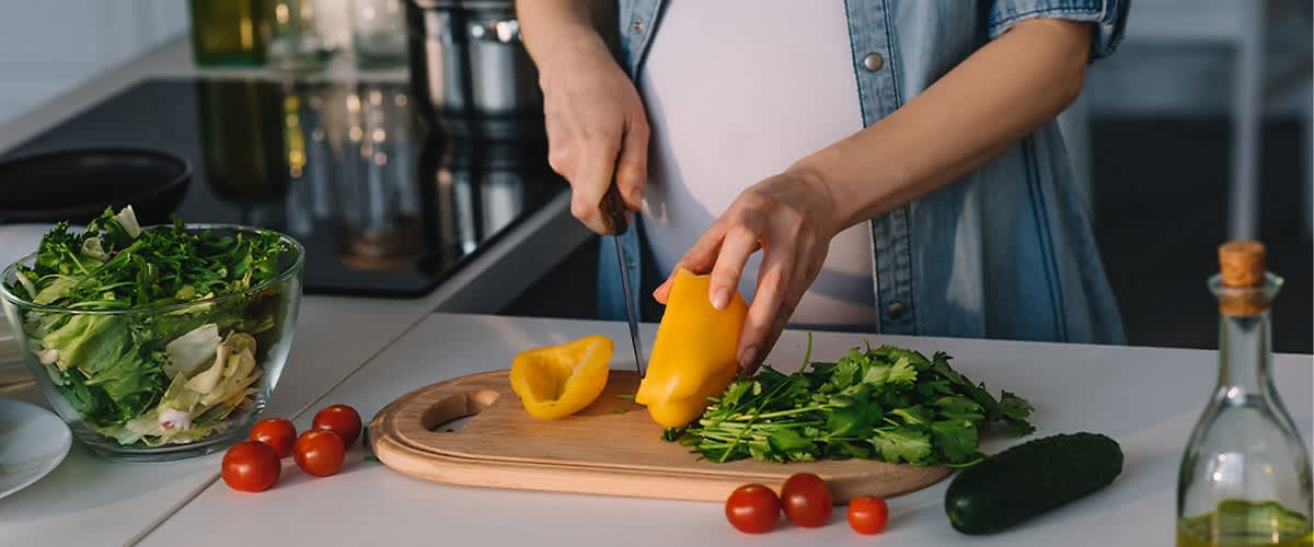 Kobieta w ciąży krojąca warzywa