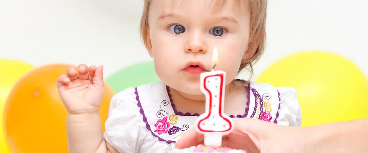 Dziecko dmucha świeczkę na swoje pierwsze urodziny