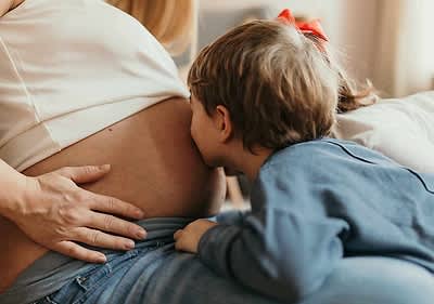 Chłopiec czekający na rodzenstwo i całujący ciążowy brzuszek mamy