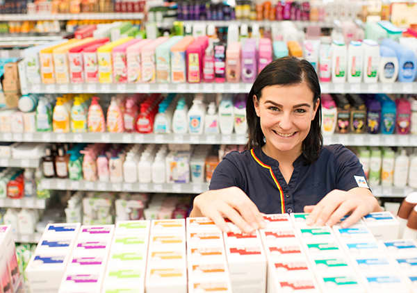 Angajatul dm aranjează produsele la raft