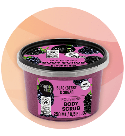 Recipientă rotundă din plastic transparent cu capac negru, conținând scrub de corp mov, etichetă roz cu textul „Blackberry & Sugar Polishing Body Scrub 250 ml / 8,5 fl. oz.” și logo-ul Organic Shop, desen cu mure și simbol COSMOS Natural, inscripție „99%”