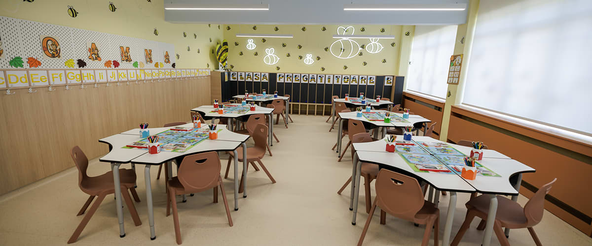 Sala de clasă pregătitoare cu mese și scaune pentru copii