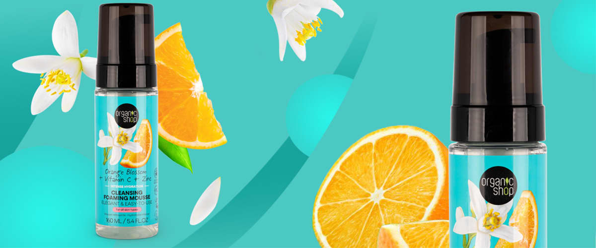 Sticle de produs cosmetic cu felii de portocală și flori pe fundal turcoaz