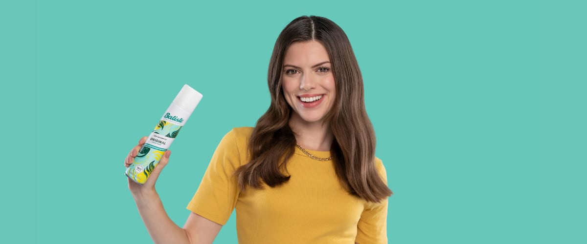 Femeie ținând un spray de șampon uscat Batiste în mână