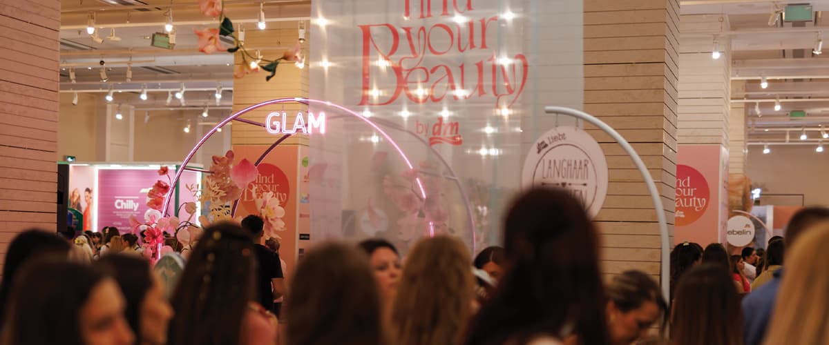 Eveniment de frumusețe în magazin cu decoruri roz, arc luminat GLAM și mulțime de participanți