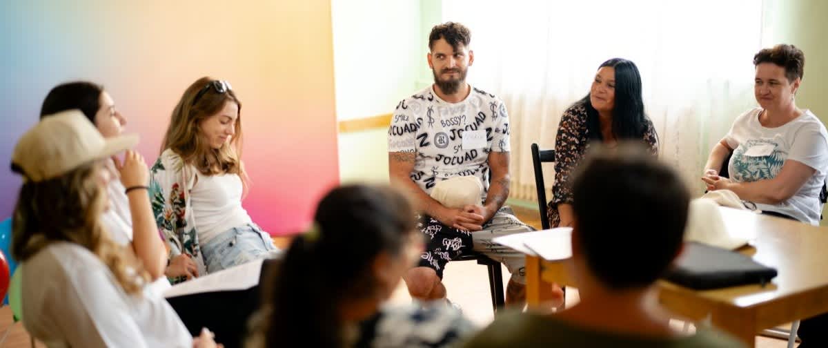 Discuție de grup informală cu persoane așezate în cerc într-o cameră luminoasă