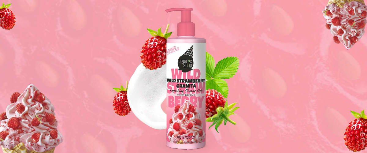 Recipientă roz cu pompă conținând spumă de duș cu etichetă Wild Strawberry Granita și imagine mică cu zmeură, în jur zmeură proaspătă, frunze verzi și textură roz ca fundal