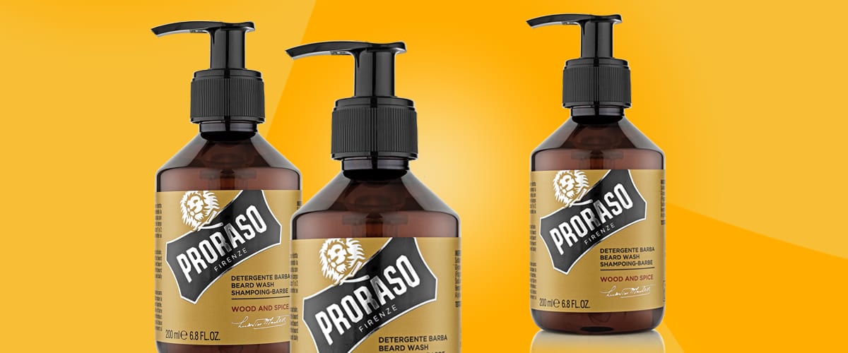 Trei flacoane cu pompă de gel pentru bărbierit și spălare a bărbii marca Proraso, sticle maro cu etichete galbene și inscripția „PRORASO”, volum 200 ml/6.8 FL OZ, plasate pe fundal portocaliu luminos