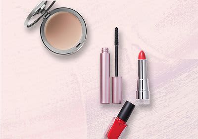 Produse cosmetice: pudră compactă, rimel, ruj roșu și ojă roșie pe fundal roz