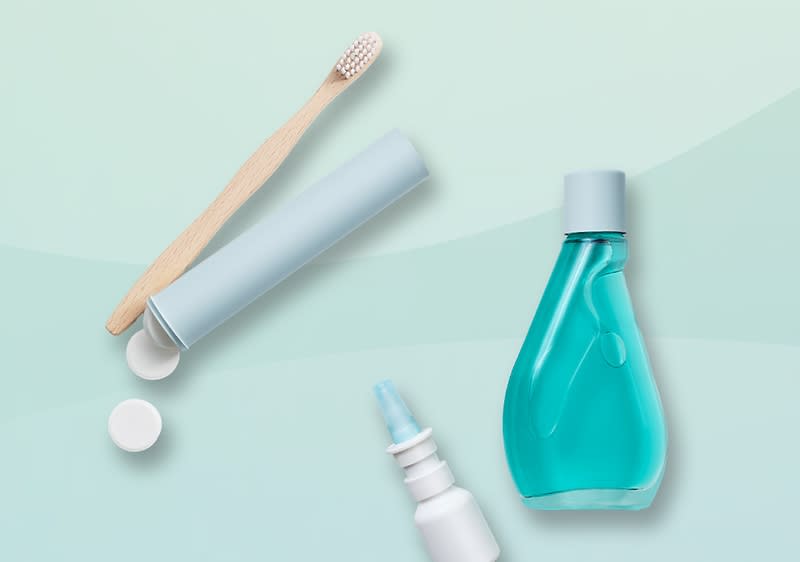 Periuță de dinți, pastă de dinți, apă de gură și spray nazal pe fundal verde.