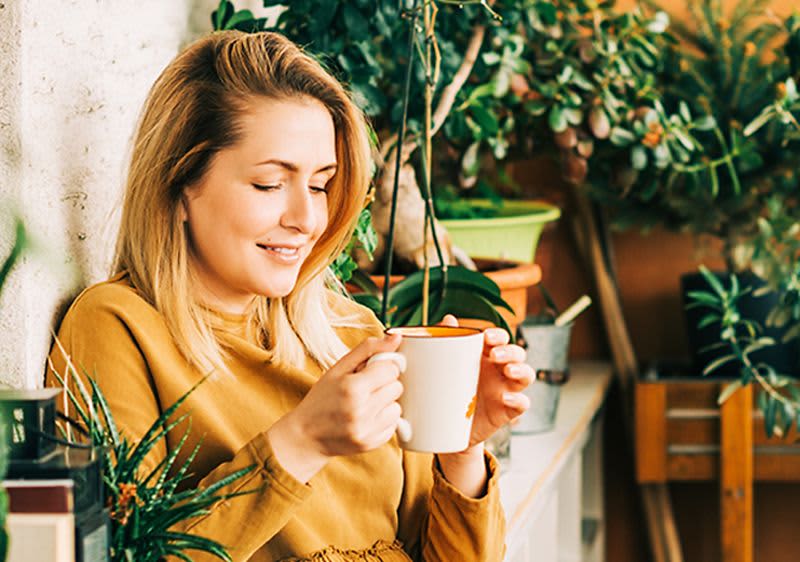 Femeie pe balcon cu o ceașcă de ceai