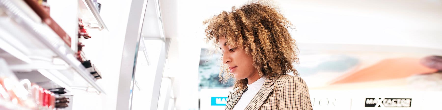 Clientă în fața unui raft cu produse de machiaj în sediul central dm.